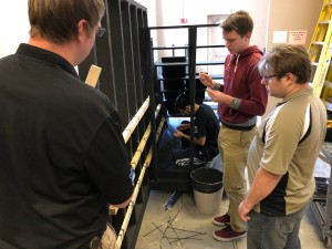 Instructor Mike Forbes working with students to install video panels on set pieces